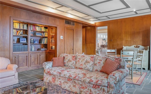 living room featuring stone finish floor, visible vents, and wood walls