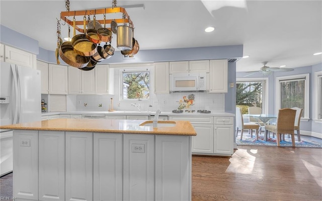 kitchen featuring a center island, a wealth of natural light, white appliances, and white cabinetry