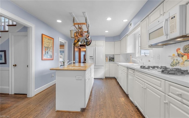 kitchen with white appliances, a kitchen island, white cabinets, and decorative backsplash