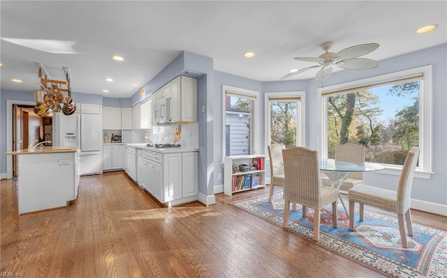 kitchen with white appliances, baseboards, light countertops, and light wood-style floors