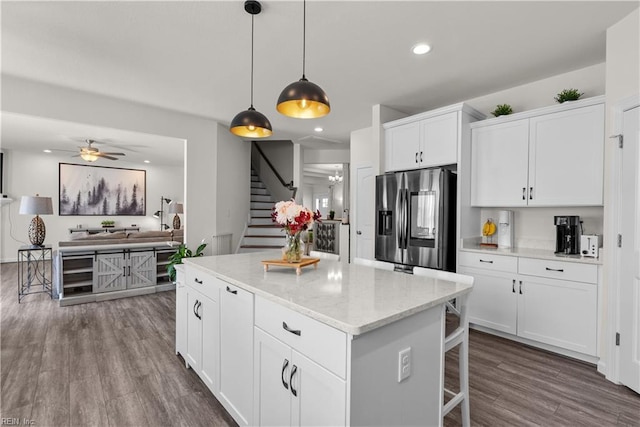 kitchen with recessed lighting, a kitchen island, white cabinets, stainless steel refrigerator with ice dispenser, and dark wood-style floors