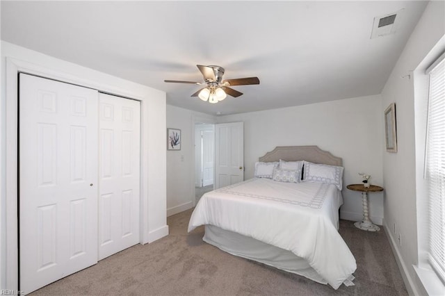 carpeted bedroom featuring baseboards, a closet, visible vents, and a ceiling fan