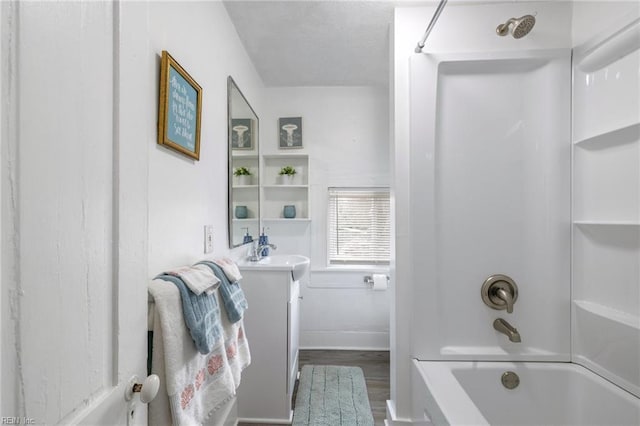 bathroom with bathtub / shower combination, vanity, baseboards, and wood finished floors