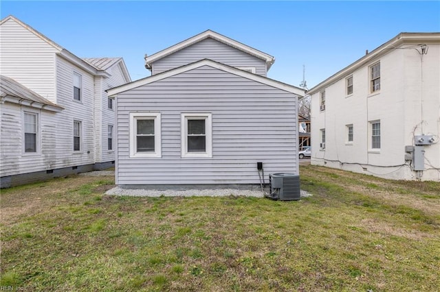 rear view of property featuring a lawn and central air condition unit