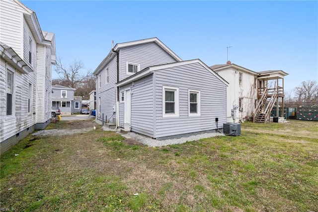 rear view of house featuring a lawn and central AC unit