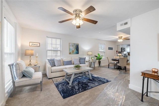 carpeted living room featuring baseboards, visible vents, and a ceiling fan