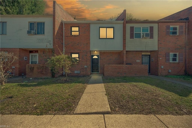 multi unit property featuring a front lawn and brick siding