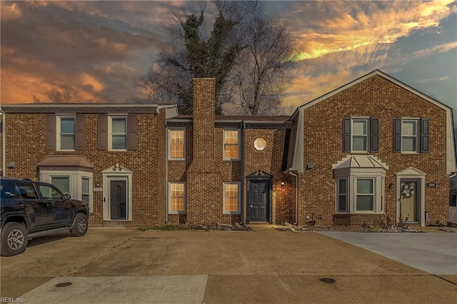 multi unit property featuring a chimney and brick siding