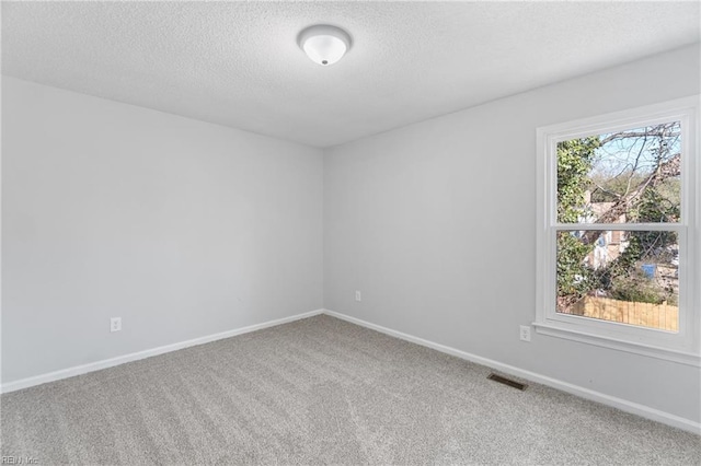 carpeted spare room with visible vents, a textured ceiling, and baseboards