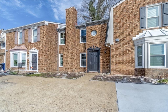 view of front of house featuring brick siding and a chimney