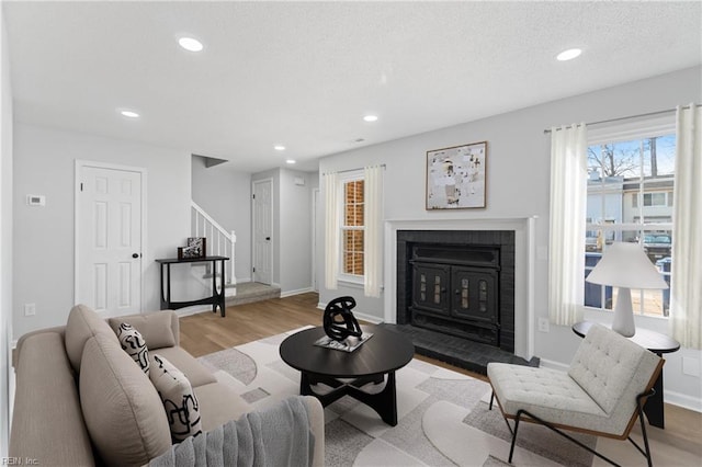 living room with stairway, a brick fireplace, wood finished floors, and recessed lighting