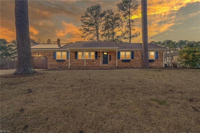 view of front facade with an attached garage, brick siding, a yard, driveway, and crawl space