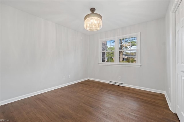 unfurnished bedroom with a notable chandelier, dark wood finished floors, visible vents, and baseboards