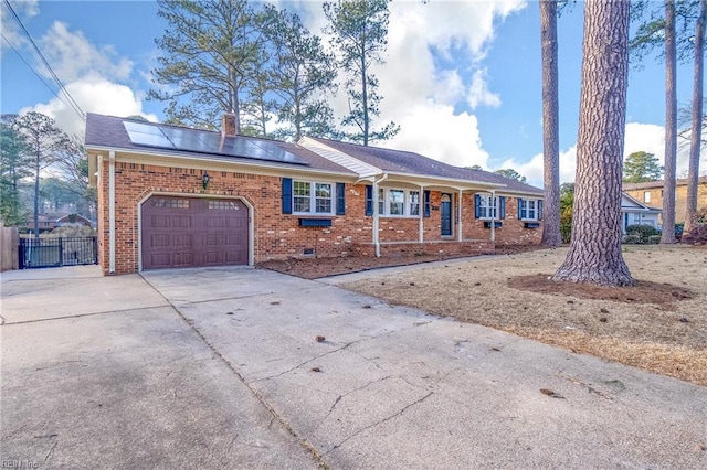 ranch-style home with brick siding, solar panels, fence, a garage, and driveway