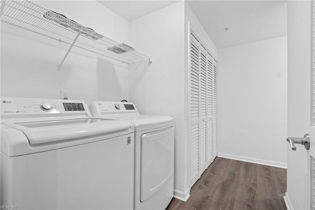 clothes washing area with dark wood-style floors, laundry area, independent washer and dryer, and baseboards