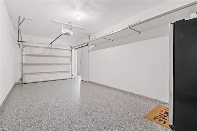 garage featuring freestanding refrigerator and a garage door opener