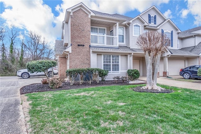 view of front of house featuring driveway, brick siding, a balcony, and a front yard