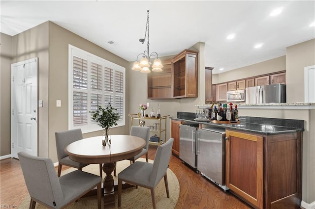 kitchen featuring brown cabinets, decorative light fixtures, recessed lighting, appliances with stainless steel finishes, and wood finished floors