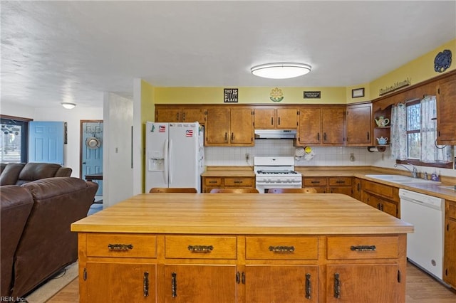 kitchen featuring light countertops, open floor plan, a sink, white appliances, and under cabinet range hood