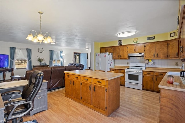 kitchen featuring a center island, light countertops, open floor plan, white appliances, and under cabinet range hood