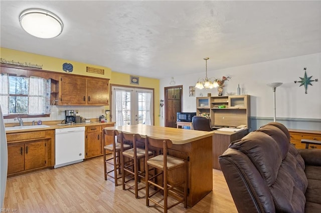 kitchen featuring dishwasher, light countertops, french doors, and brown cabinetry