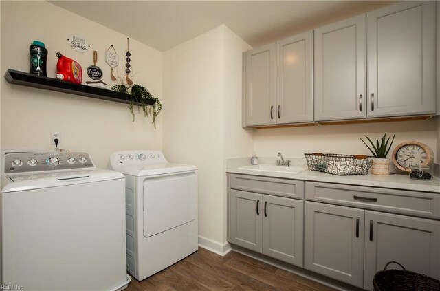 laundry room featuring cabinet space, dark wood finished floors, a sink, and washing machine and clothes dryer