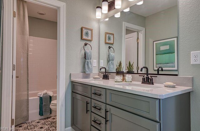 bathroom featuring double vanity, shower / tub combo, a sink, and toilet