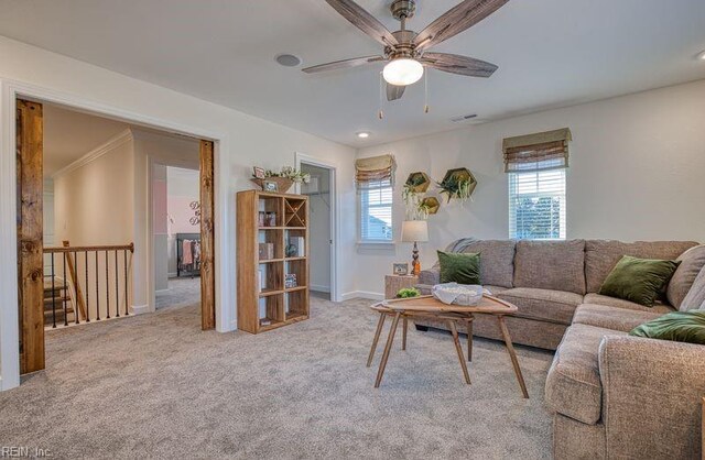 living room featuring ceiling fan, baseboards, and light colored carpet