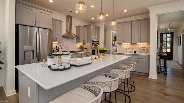 kitchen with stainless steel appliances, crown molding, wall chimney range hood, and gray cabinetry