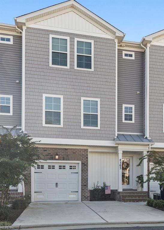 view of property featuring a garage, brick siding, and driveway