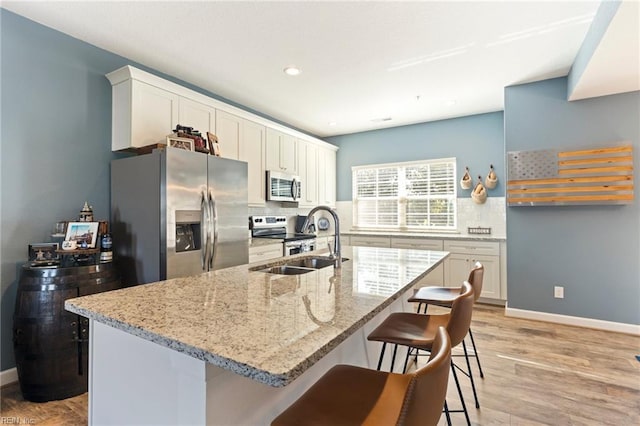 kitchen featuring a kitchen bar, appliances with stainless steel finishes, decorative backsplash, and a sink