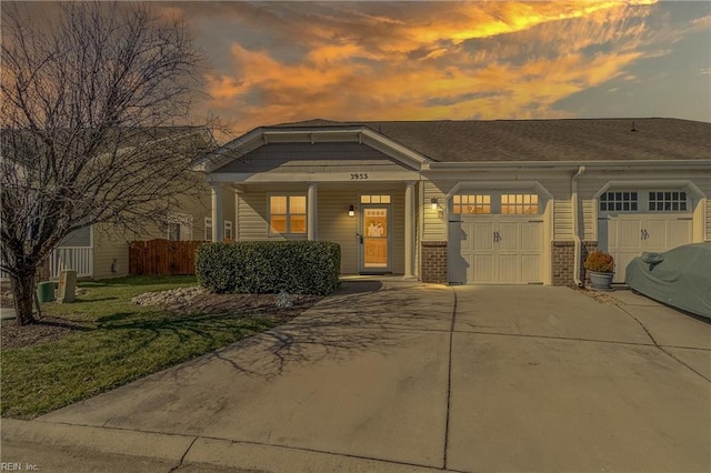 view of front of home featuring driveway, a garage, brick siding, fence, and a front yard