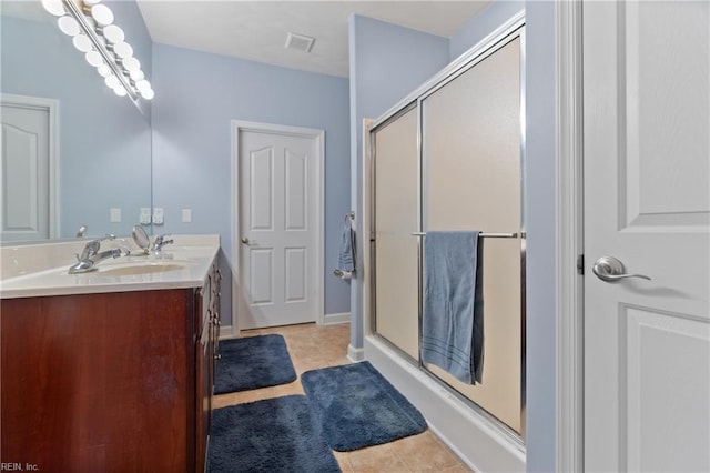 full bathroom featuring double vanity, tile patterned flooring, a sink, and a shower stall