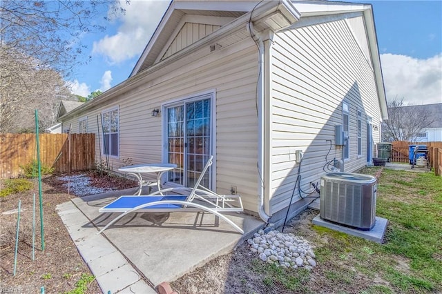 rear view of property featuring board and batten siding, a patio, fence, and central AC unit