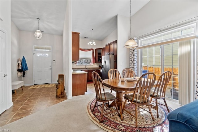 dining room featuring light tile patterned floors, light colored carpet, an inviting chandelier, vaulted ceiling, and baseboards