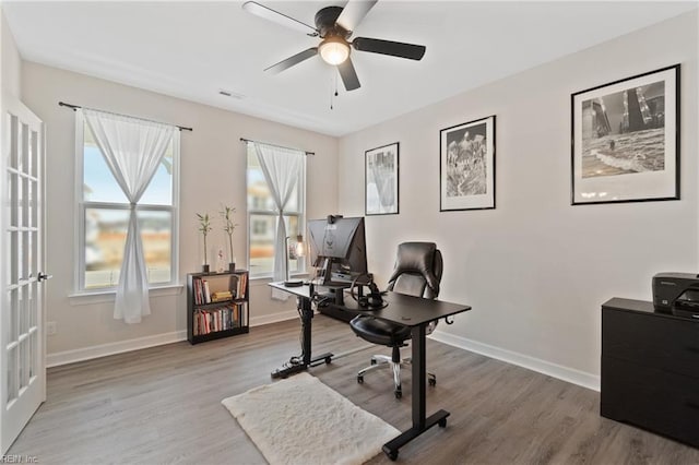 home office with visible vents, ceiling fan, baseboards, and wood finished floors