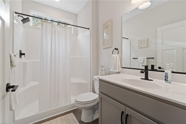 full bathroom with wood finished floors, a stall shower, vanity, and toilet