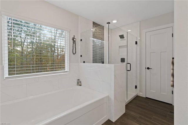 bathroom featuring wood finished floors, recessed lighting, a garden tub, and a shower stall