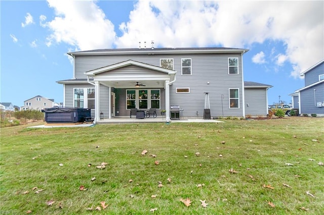 back of house with a patio area, ceiling fan, a hot tub, and a lawn