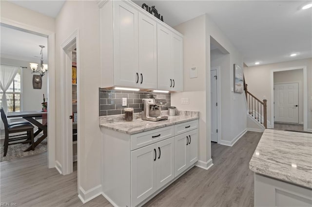 kitchen featuring light wood-style flooring, white cabinetry, decorative backsplash, and baseboards