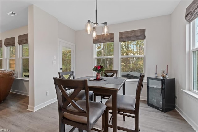 dining space featuring light wood-type flooring, visible vents, a notable chandelier, and baseboards