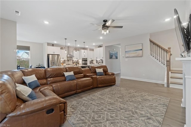 living room featuring ceiling fan, recessed lighting, visible vents, stairs, and light wood-type flooring