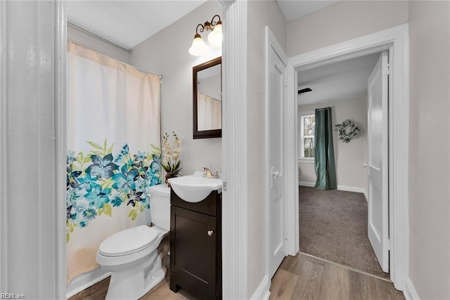 bathroom with baseboards, vanity, toilet, and wood finished floors