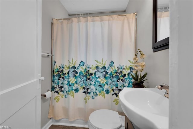 full bathroom with toilet, shower / bath combo with shower curtain, and a sink