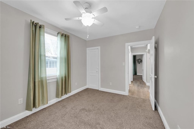 unfurnished bedroom featuring carpet floors, baseboards, and a ceiling fan