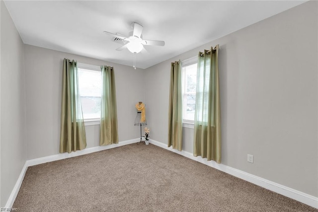 empty room featuring carpet floors, baseboards, a ceiling fan, and a wealth of natural light