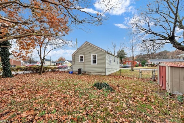 back of property featuring central air condition unit, a storage shed, fence, and an outdoor structure