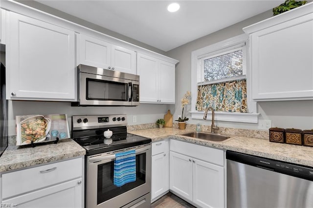 kitchen with stainless steel appliances, recessed lighting, white cabinetry, and a sink