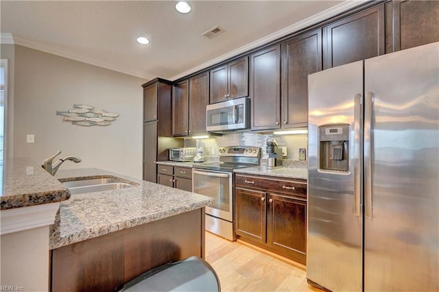 kitchen featuring stainless steel appliances, a sink, visible vents, and crown molding