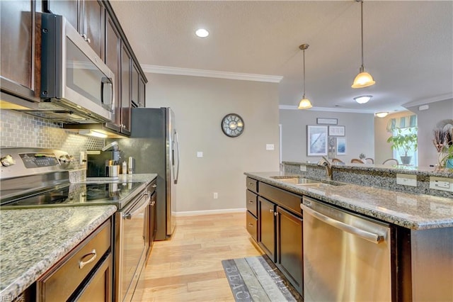 kitchen with hanging light fixtures, decorative backsplash, appliances with stainless steel finishes, ornamental molding, and a sink